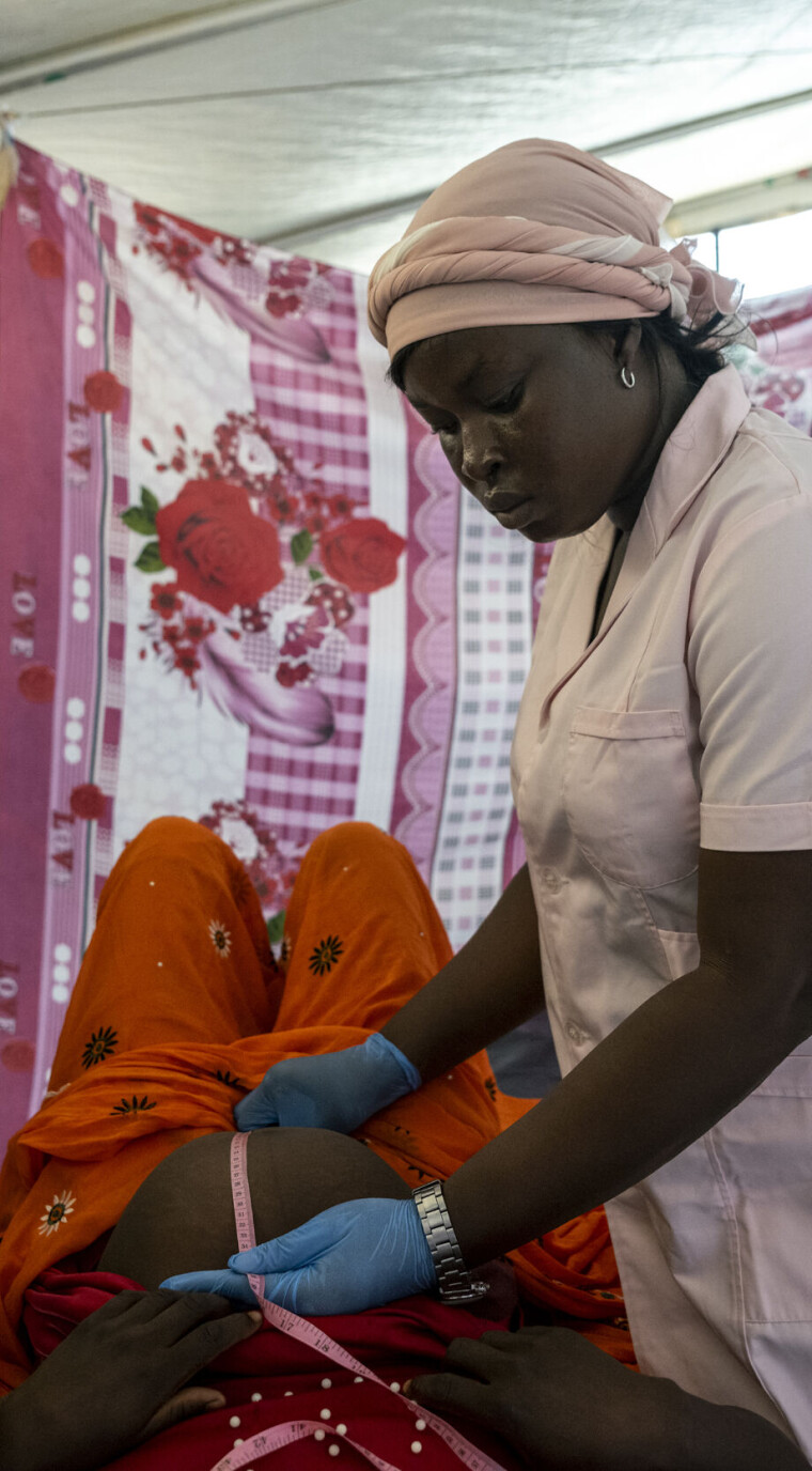 Nancy Symgambaye måler magen til Taiba Baraka under en svangerskapskontroll i en leir for sudanesiske flyktninger i Tsjad.