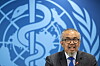 Tedros Adhanom Ghebreyesus taler foran WHOs blå logo under en pressekonferanse.