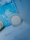 En beholder med hvit brystmelk står i en kjøleboks av blå plast.