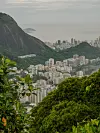 Utsikt over Rio de Janeiro med tett bebyggelse mellom grønne åser og havet i bakgrunnen.