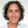 Nærbilde av en person med mørkt hår foran lys bakgrunn.