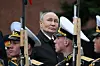 Vladimir Putin står bak soldater i paradeuniform under en seremonis ved Kreml-muren i Moskva.