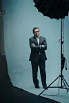 Dan Banik står med armene i kors foran en lys bakgrunn i et fotostudio.