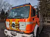 Oransje og hvit Mercedes-Benz brannbil parkert ved vei.