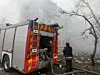 Brannbil ved en røykfylt bygning, med en brannmann i forgrunnen.