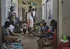 Mødre sitter på gulvet i en sykehuskorridor og venter utenfor nyfødtintensiven i Kasungu, Malawi.
