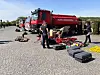 Brannmannskap står ved en rød tankbil med utstyr lagt utover bakken i en by i Lviv-regionen i Ukraina.