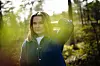 Frøya Skjold Sjursæther står utendørs ved vindturbinene og holder en hånd mot håret.
