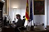 Person sitter ved en skrivepult i et kontor med spansk og EU-flagg ved siden av vinduet.