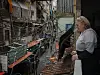Kvinne står på en balkong og ser utover tettbygde boligblokker i Shatila i Beirut.