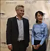 To personer står foran en vegg med teksten «Aung San Suu Kyi» og «World Freedom Fund».