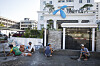 Arbeidere pusser fasaden til Telenor-bygget i Yangon mens en annen sitter foran inngangen.