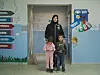 Khaltoum Ahmed Hassan står i en døråpning med to små barn i et rom i Bar Elias i Libanon.