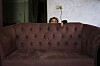 En liten jente kikker over ryggen på en brun sofa i et hjem i Gaza by.