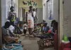 Mødre sitter på gulvet i en sykehuskorridor og venter utenfor nyfødtintensiven i Kasungu, Malawi.