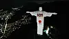 Christ the Redeemer-statuen med «SOS Venezuela» og Caritas-logo sett fra luften om natten.