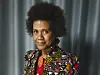 Maria Sarungi Tsehai står foran et grått forheng iført fargerik jakke.