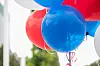 Røde og blå ballonger henger tett sammen foran en lys bakgrunn.