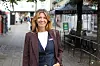 Kvinne står i en gågate med restauranter og uteservering i bakgrunnen.