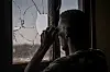 Sudansk soldat bruker kikkert ved et knust vindu i Khartoum Nord.