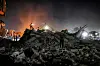 En person står på ruiner mens redningsmannskaper arbeider i mørket etter et bombardement i Khan Yunis.