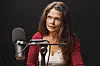 Cecilie Hellestveit sitter ved en mikrofon i et mørkt podcaststudio.