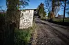Graffitidekorert mur langs en grusvei med trær og vegetasjon.