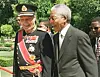 Kong Harald i uniform og Nelson Mandela i dress står sammen i en hage i Cape Town.