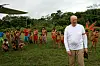 Kong Harald står foran yanomamifolk i en gresskledd landsby i Amazonas.