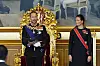 Kong Haakon VIII sitter på en utsmykket tronstol, mens kronprinsesse Ingrid Alexandra står ved siden av i Stortinget.