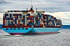 Stort containerskip lastet med fargerike fraktcontainere seiler på sjøen.