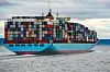 Stort containerskip lastet med fargerike fraktcontainere seiler på sjøen.