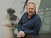 Jan Olav Andersen står foran en informasjonsvegg med tekst og bilde av en soppsky.