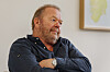 Jan Olav Andersen sitter med armene i kors i et rom med et innrammet kart på veggen.