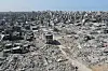 Flyfoto av mennesker som går gjennom omfattende ødeleggelser i Gaza City.
