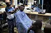 Frisør klipper håret til en kunde i en opplyst salong i Tanzania.
