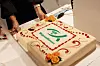 Dekorert kake med Misjonsalliansens logo og blomsterpynt på et bord.
