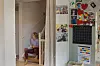 Heidi Sandvand Hegertun sitter i en trapp hjemme, omgitt av bilder og fargerik veggdekor.
