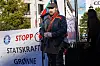 Beaska Niillas står ved et demonstrasjonsbanner mot Statkraft foran Stortinget.