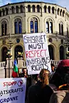 Demonstranter holder skilt mot Statkraft foran Stortinget med krav om respekt for urfolks rettigheter.