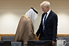 To menn står ved et konferansebord, den ene i arabiske klær og den andre i mørk dress.