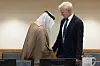 To menn står ved et konferansebord, den ene i arabiske klær og den andre i mørk dress.