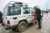 Jan Egeland står ved en NRC-merket terrengbil på et gjørmete område i Kabul.