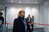 Kvinne står foran en rød sperrelinje i et innendørs arrangementsområde.