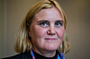 Portrett av blond kvinne i mørke klær og fargerikt skjerf mot en uskarp bakgrunn.