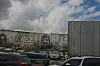Graffitimaleri på en betongvegg ved et industriområde med parkerte biler foran.