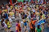 Stor, fargerik folkemengde danser og beveger seg gjennom en gate.